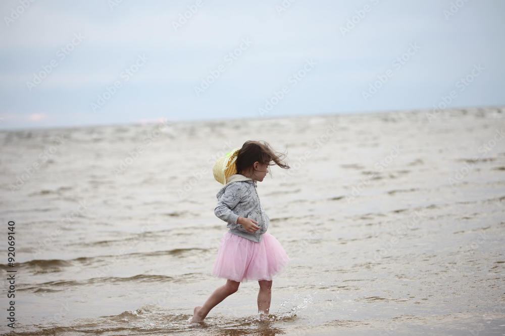 Little girl walking in waves against sea and sky Little girl walking in waves against sea and sky