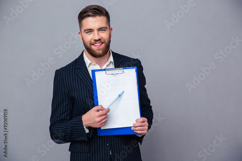Smiling businessman showing blank clipboard