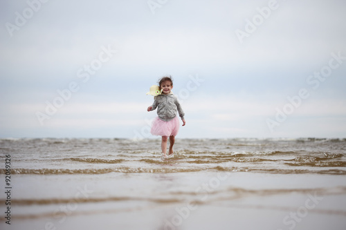 Little girl going in waves against sea and sky