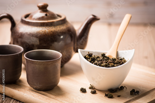  dry tea leaf in ceramic bowl wit pot on wood background