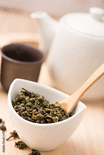  dry tea leaf in ceramic bowl wit whith pot on wood background