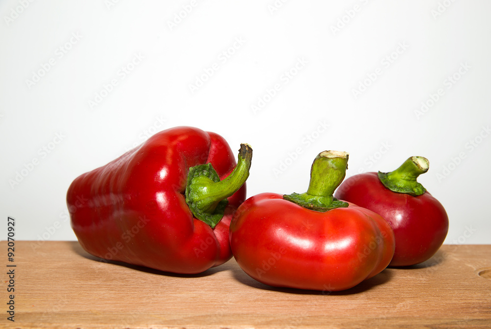 Three ripe red peppers on over white