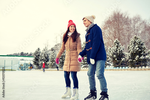 happy couple ice skating on rink outdoors