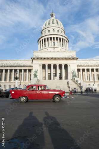 Shadows of pedestrians passing in front of classic American car near the Capitolio building in Central Havana