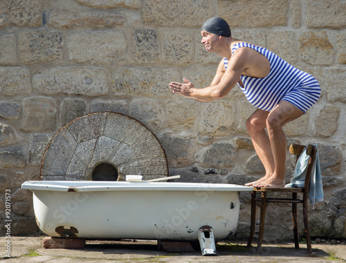 man in retro swimsuit jumps to the outdoor bathtub photo