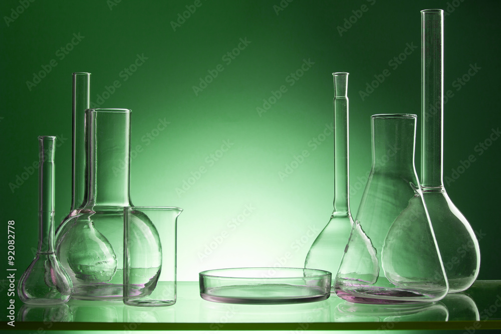 Assorted empty laboratory glassware, test-tubes. Green tone medical background. Copy space