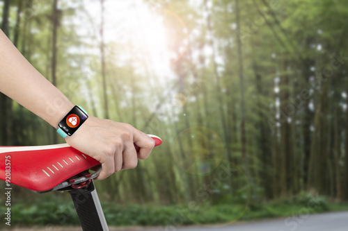 Woman hand holding bike seat wearing health sensor smart watch