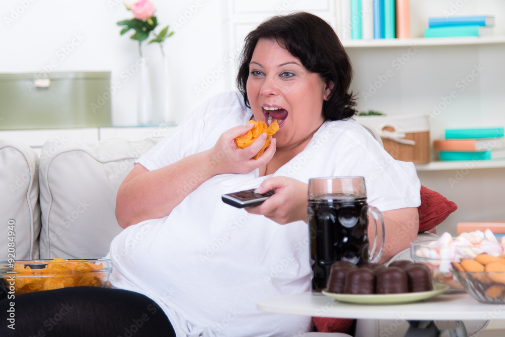 übergewichtige frau isst chips auf dem sofa