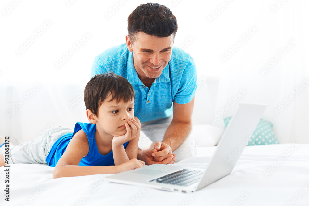Father and son having fun using laptop