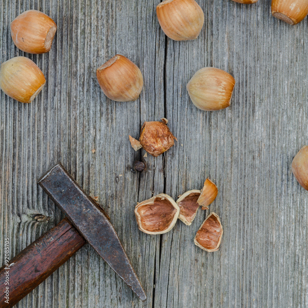 cracked nuts and hammer on old wooden background