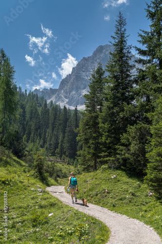 Alpine trail Woman with dog is hiking in the Alps
