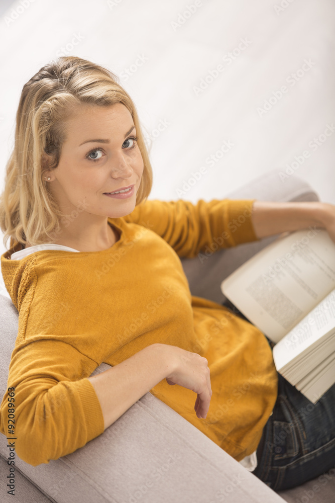Naklejka premium young woman reading a book at home