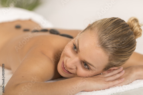 young woman getting hot stone massage in spa salon