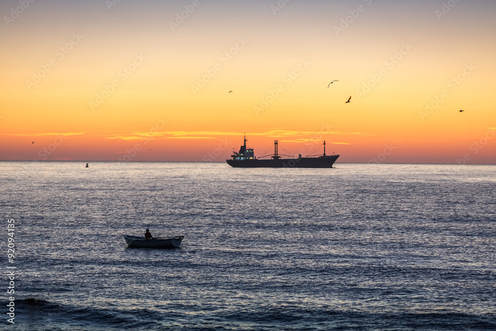 Fisherman sailling with his boat on beautiful sunrise over the sea