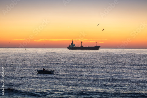 Fisherman sailling with his boat on beautiful sunrise over the sea © ValentinValkov