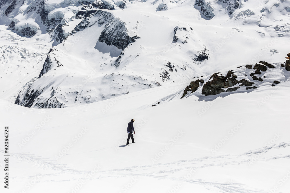 Man walking on the snow with the background of snow mountain.