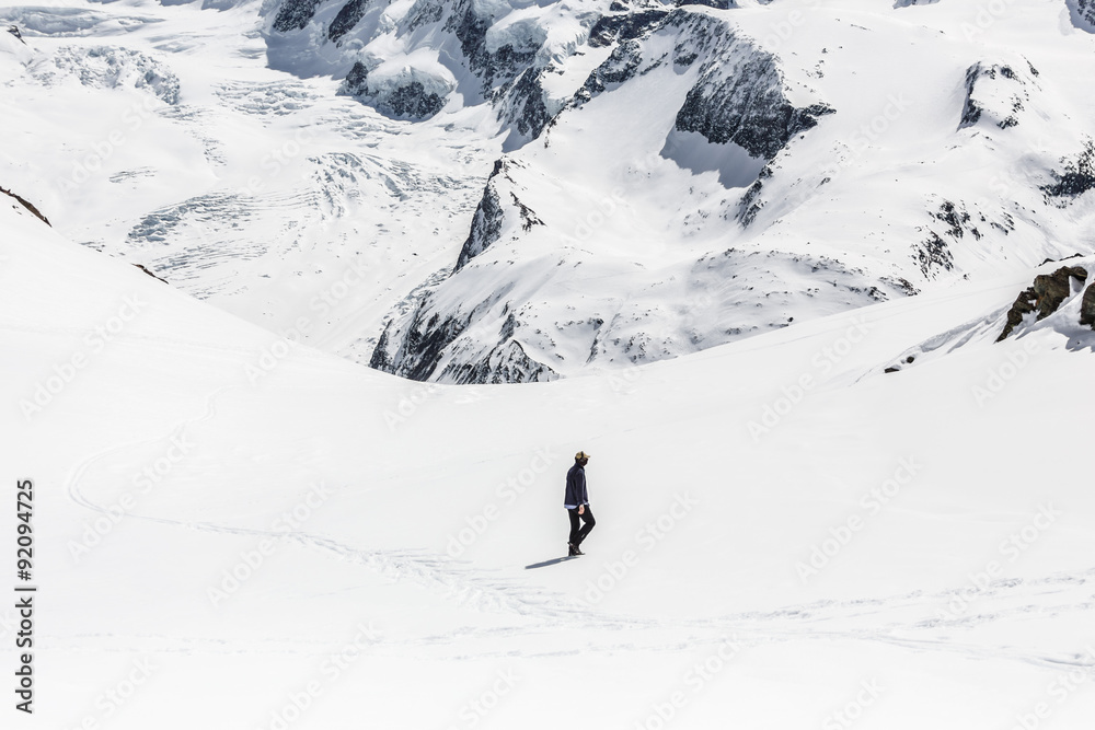 Man walking on the snow with the background of snow mountain.
