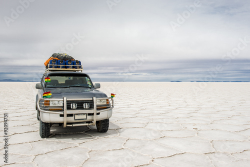 In the Salt Desert of Uyuni, in Bolivia, an off-road car with little flags of Bolivia, stay in the side. It’s ready for adventure photo