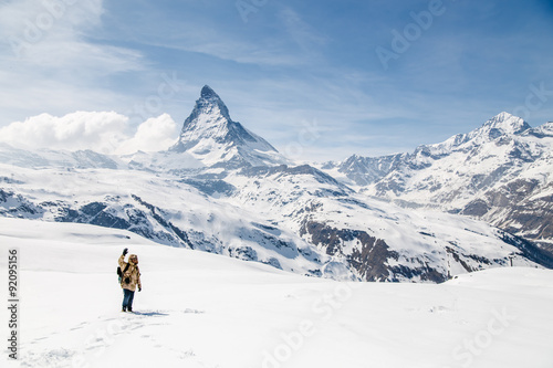 A man waving his hand standing on the snow in the background of Matterhorn. © pathara