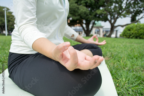 Young Asian fitness woman doing yoga outside on grass