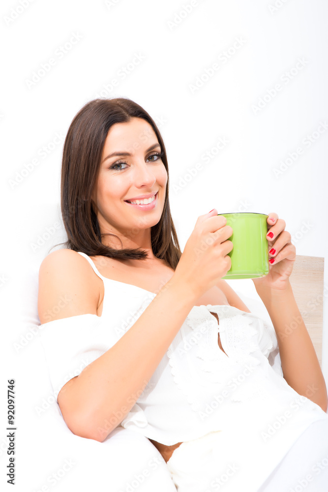 Beautiful young woman having her first coffee in bed