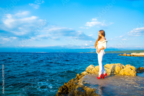 Beautiful young woman looking at the ocean.