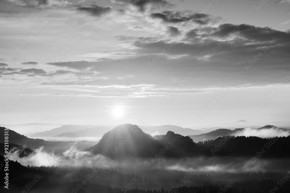 Autumn sunrise panorama  in a beautiful mountain within inversion. Peaks of hills increased from heavy  fogg