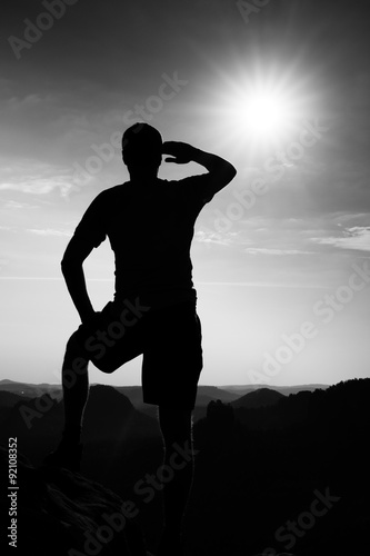 Hiker on edge of sandstone cliff in rock empires park and watching over the misty valley to Sun. Beautiful moment the miracle of nature photo