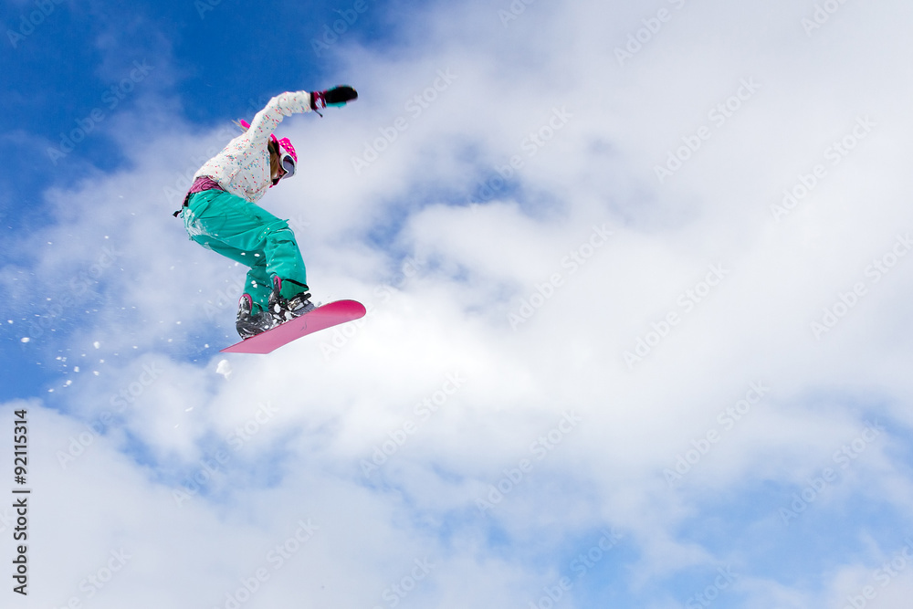 Female snowboarder making an awesome big jump of a kicker