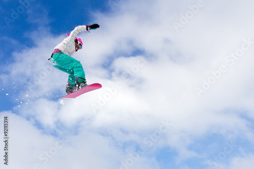 Female snowboarder making an awesome big jump of a kicker
