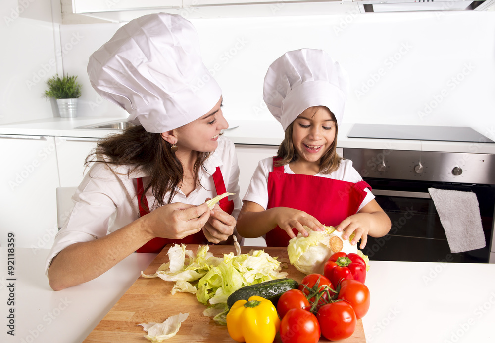 happy mother and little daughter at home kitchen preparing paprika salad in cook hat happy mother and little daughter at home kitchen preparing paprika salad in cook hat