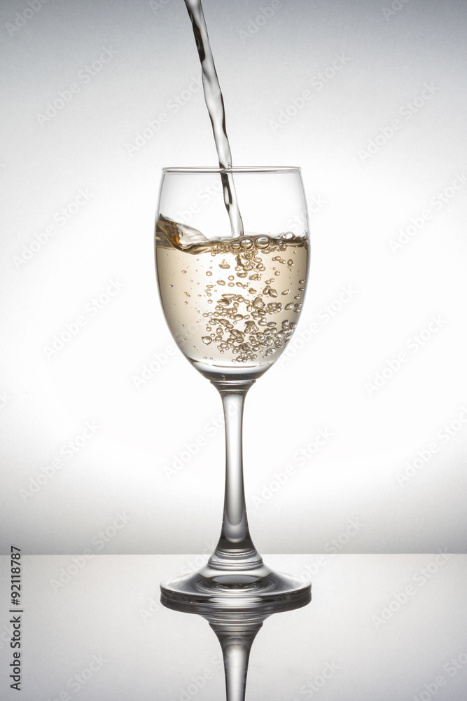 White wine pouring into wineglass on white background White wine pouring into wineglass on white background