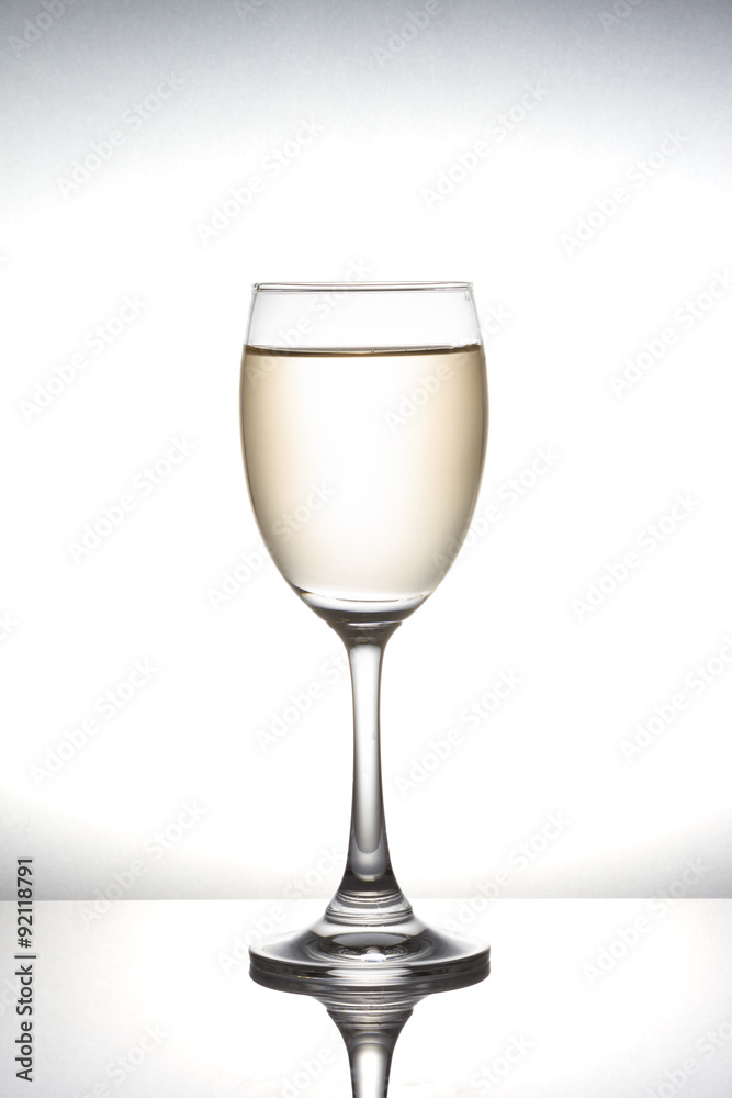 White wine pouring into wineglass on white background