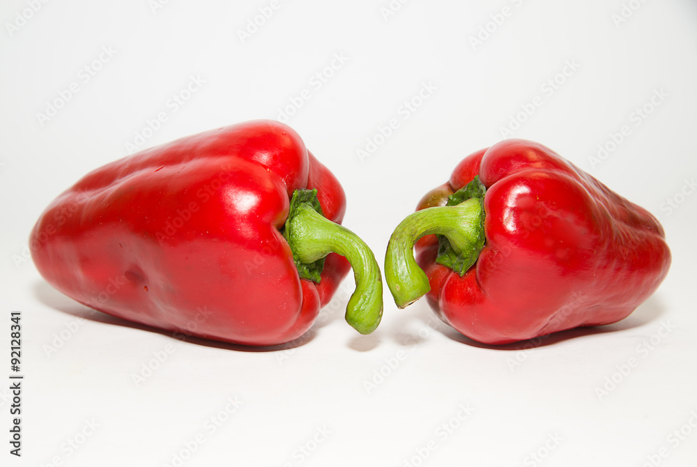 Two ripe red peppers on over white Two ripe red peppers on over white