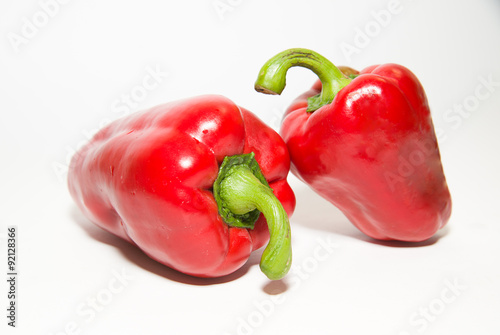 Two ripe red peppers on over white