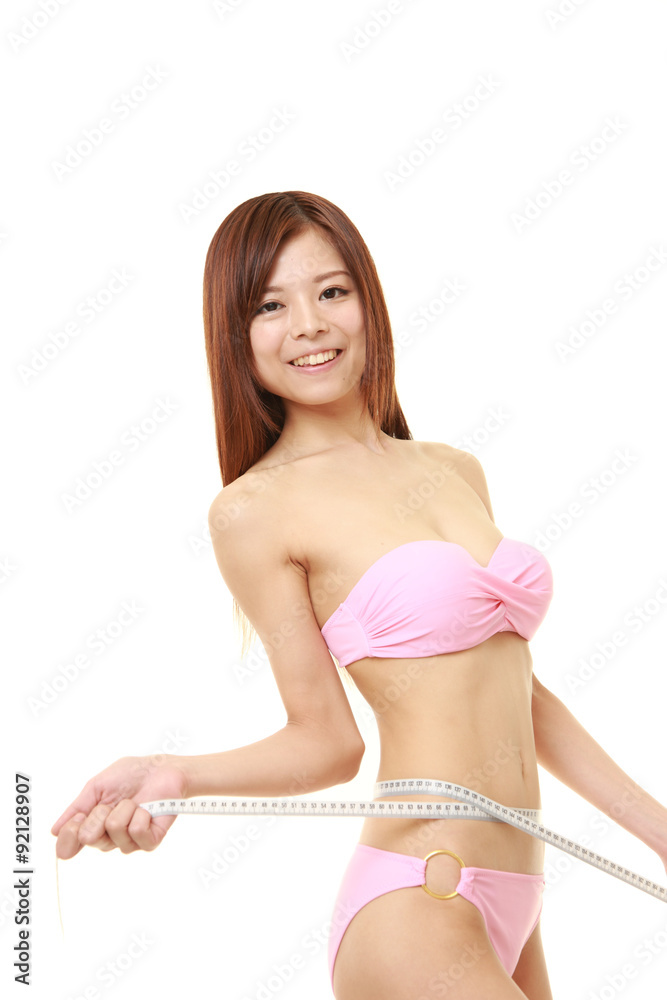 young Japanese woman in a pink measuring her waist Stock Photo | Adobe