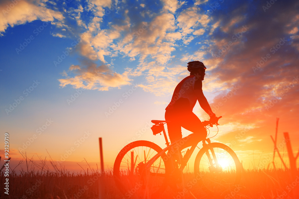 Silhouette of a biker and bicycle on sunset background.