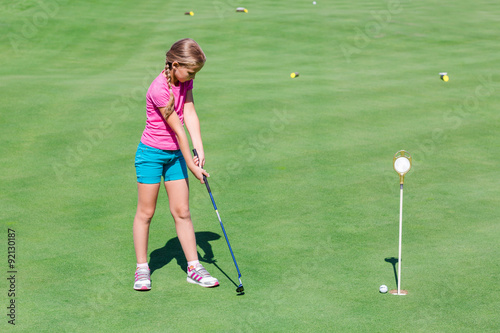 Cute little girl playing golf on a field