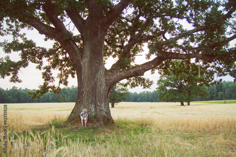 kid stands near a tree
