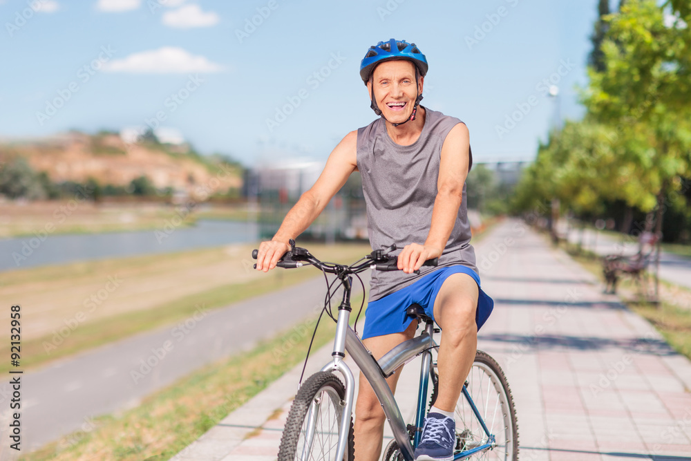 Fototapeta premium Cheerful senior biker posing on a sidewalk