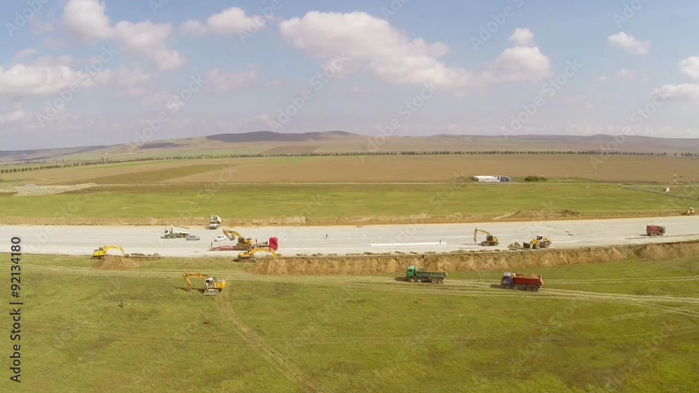 Heavy construction equipment working on an airport runway, aerial view Heavy construction equipment working on an airport runway, aerial view