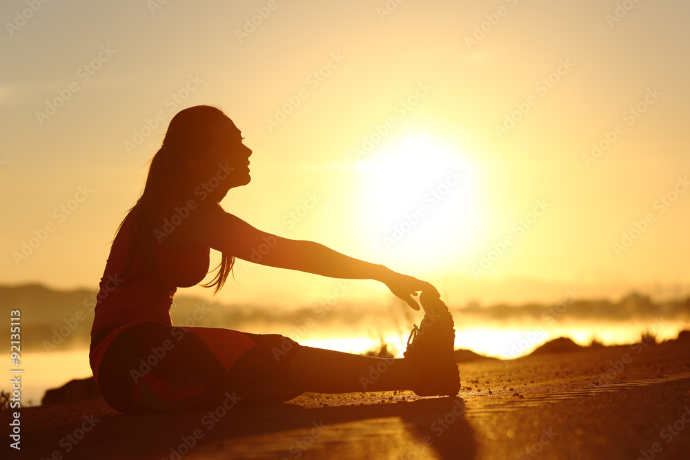 Silhouette of a fitness woman stretching at sunset - obrazy, fototapety, plakaty 