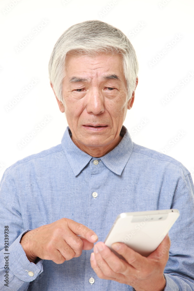 senior Japanese man using tablet computer looking confused senior Japanese man using tablet computer looking confused