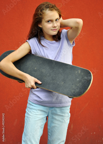 young teenage girl with skateboard in the street