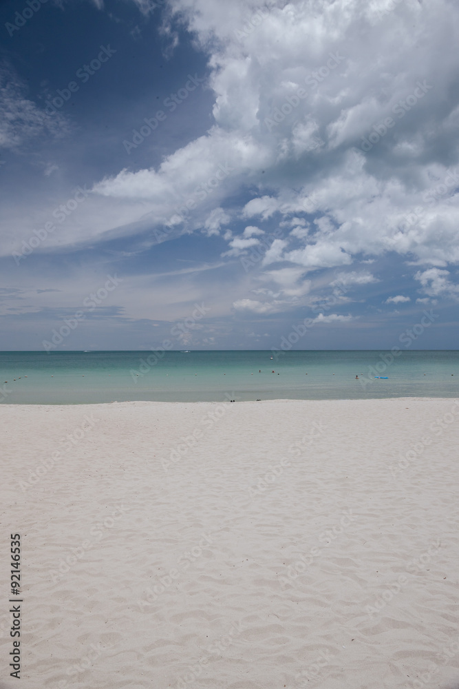 Beach on tropical island. Clear blue water, sand, clouds. 