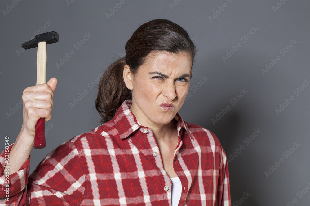 angry 30s woman holding hammer for aggression or self-defense angry 30s woman holding hammer for aggression or self-defense
