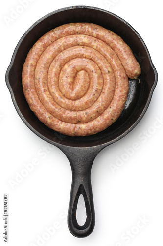 raw cumberland sausage, spiral pork sausage on skillet isolated on white background
