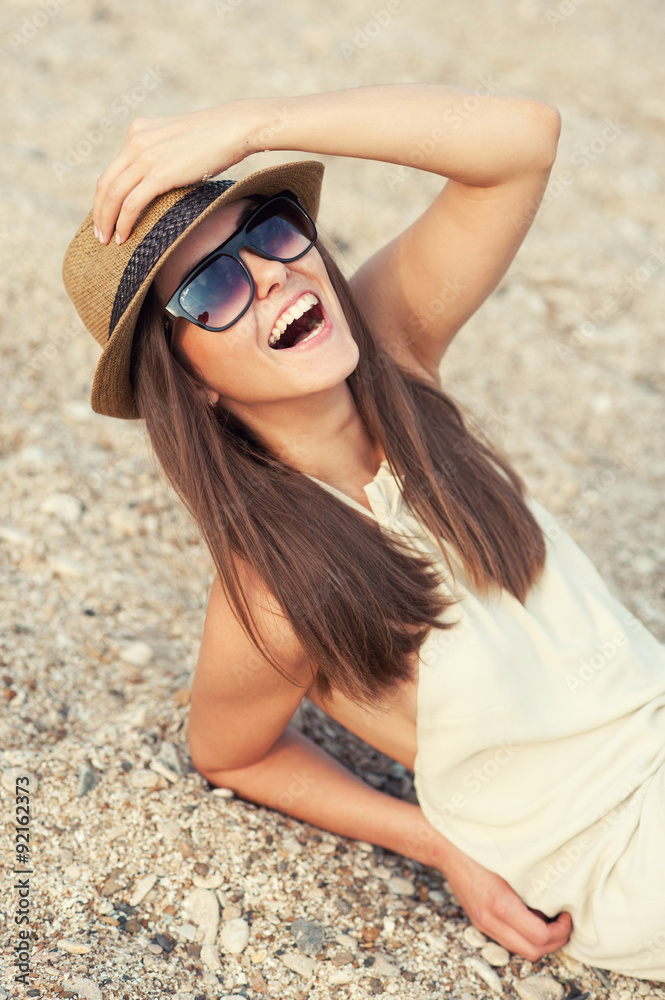 Happy smiling hipster woman in hat on a beach.