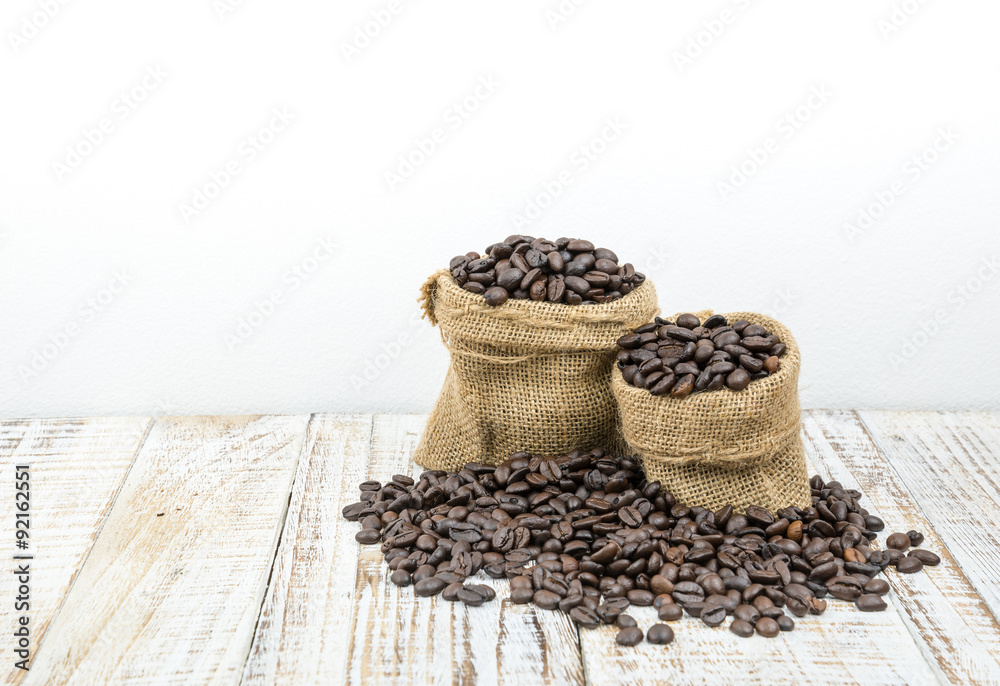 Roasted coffee beans in a sack on a wooden background Roasted coffee beans in a sack on a wooden background