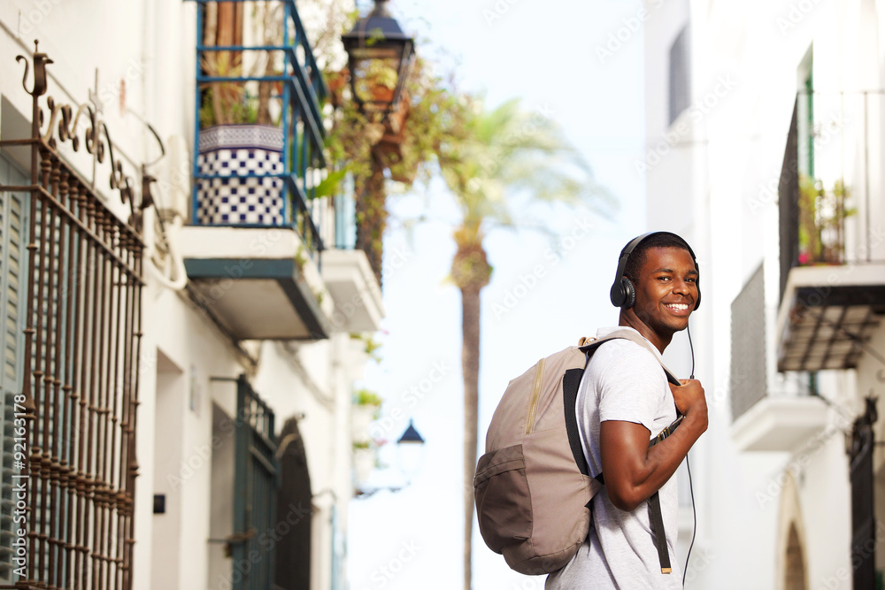 Smiling african travel man with bag listening to music